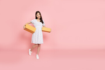 Happy Asian woman holding package parcel box isolated on pink background, Delivery courier and shipping service concept