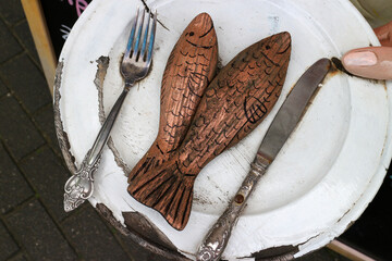 Fische aus Holz mit Messer und Gabel auf einen Teller montiert