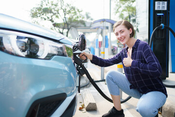 Happy beautiful caucasian white woman driver preparing to recharge her electric vehicle or EV car...