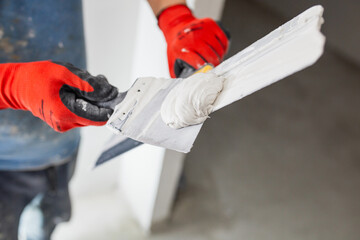Leveling the walls with white putty - the hands of a master with a spatula