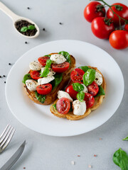 Caprese Bruschetta with fresh tomatoes, mozzarella and Basil leaves on light background. Vegetarian food