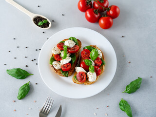 Caprese Bruschetta with fresh tomatoes, mozzarella and Basil leaves on light background. Vegetarian food