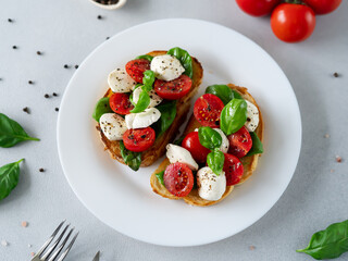 Toast with mozzarella cheese, tomatoes and basil leaves on light background. Italian food