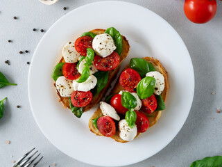 Toast with mozzarella cheese, tomatoes and basil leaves on light background. Italian food. Top view