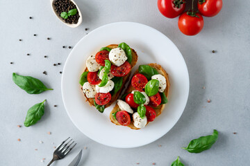 Caprese Bruschetta with fresh tomatoes, mozzarella and Basil leaves on light background. Vegetarian food. Top view