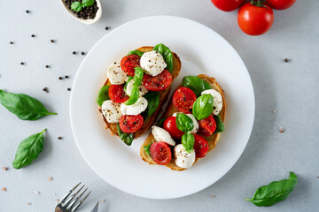 Top view of Bruschetta with tomatoes, mozzarella and basil leaves on light background. Crostino Caprese