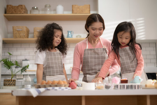Asian mom and mixed race two kid enjoy with make a cake in kitchen for celebration in mother's day.