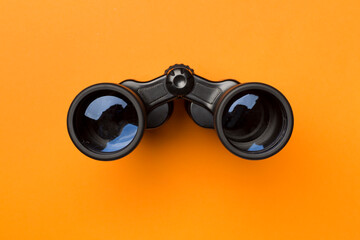 Black binoculars on color background. Top view