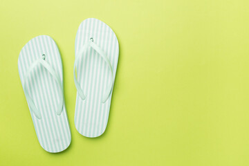 Striped flip flops on color background, top view