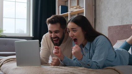 Excited Caucasian married couple lying on bed at home win laptop achievement read amazing news online bet victory celebrate success happy woman wife and man husband scream shout good Generative AI