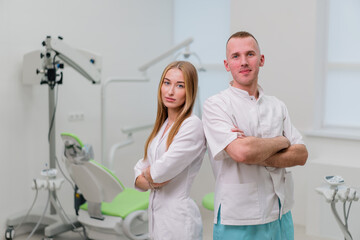 portrait of beautiful young smiling colleagues of dentists standing in the dental office before the start of the procedure