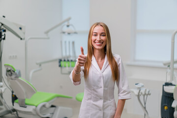 portrait of a beautiful young smiling doctor dentist standing in the dental office before the procedure