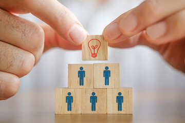 Man holding a wooden cube with light bulb on it. Teamwork and employment business concept