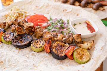 Grilled kebab with pita bread and vegetables on tray in summer fast food street cafe