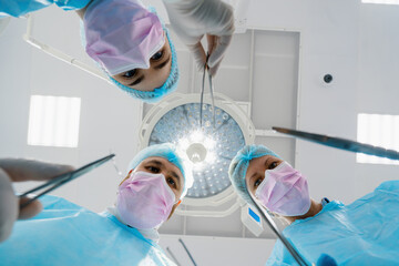 Group of doctors surgeons and nurses holding scalpels of surgical instruments during operation in hospital bottom view