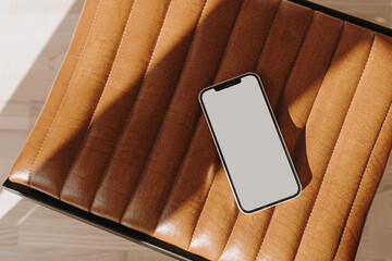 Mobile phone with copy space screen on leather bench with aesthetic sunlight shadows