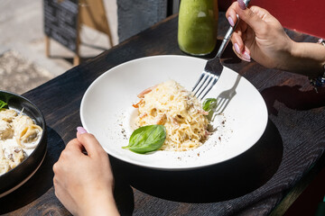 Woman eating italian pasta sitting at the cafe counter looking to the window, having lunch