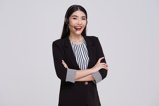 Happy young asian business woman call center. Welcome female operator put on smalltalk headphone standing on isolated white background.