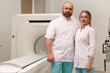 Obraz premium smiling and satisfied doctors in uniform posing near magnetic resonance imaging machine concept of professions and medicine