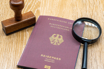 A German passport is stamped on a wooden table in an official process of authentication.