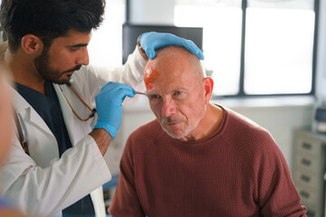Close-up of doctor treating injury of senior man.