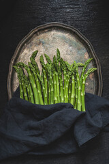 Green asparagus on a vintage tray. Dark background. Top view with copy space.