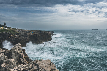 Fototapeta na wymiar Coastline with atlantic ocean in Cascais, Portugal. Waves at the shore and rocky hills