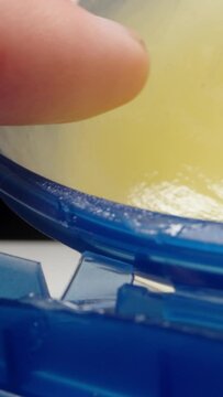 With my finger I take vaseline from a blue jar, on a black background. Dolly slider extreme close-up. Vertical video.