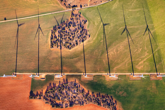 Aerial view of wind turbines in a row with large shadows over an agricultural field in a wind farm producing electricity sustainable energy at sunset. Renewable Energy, Wind Energy, Spain