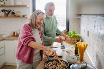 Senior couple cooking together in their kitchen.