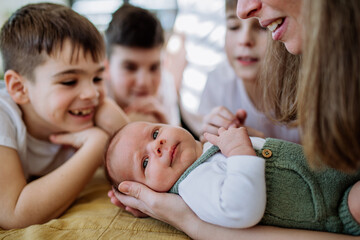 Mother and her sons cuddling their newborn baby.