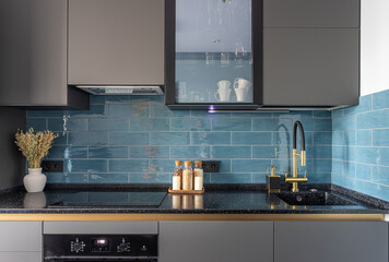 kitchen interior, gray facades, induction hob, blue tiles on the wall, black sink