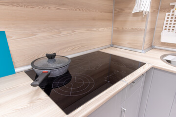 a frying pan with a lid stands on an induction stove in the kitchen