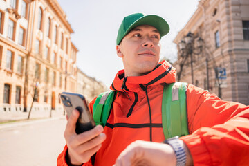 A satisfied courier is a man delivering a food order to the office to a client using an app for...