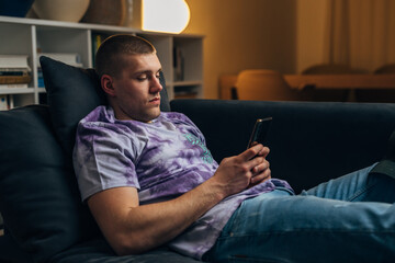 Side view of a Caucasian man using his mobile phone at home.