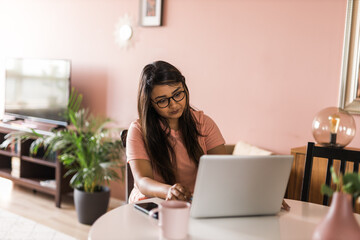 Latino or indian woman use their laptop in living room to make video calls. Video call and online chat with family