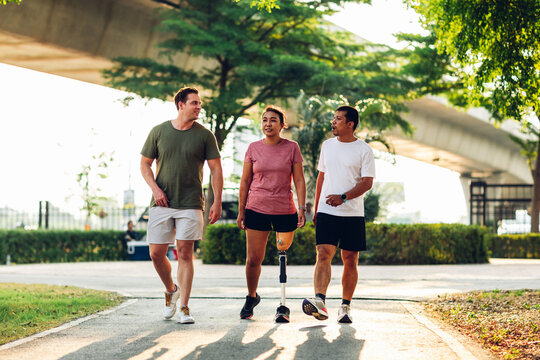 Friend support Friend with a prosthetic leg while exercising outdoor. People walking together on park outdoor. Exercise walking  woman with prosthetic leg and friend support together in  park outdoor