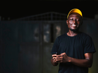 young black man using mobile device while smiling at the camera.
