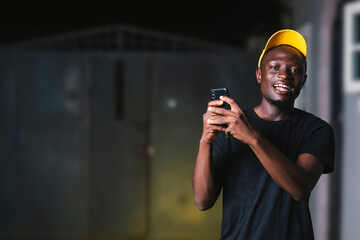 young black man using mobile device while smiling at the camera.