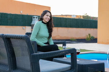 Young Latin woman drinking wine in the garden of the villa at sunset