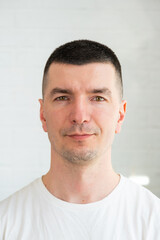 Fototapeta premium Portrait of a man in close-up on a white background in a white T-shirt. Photos for documents