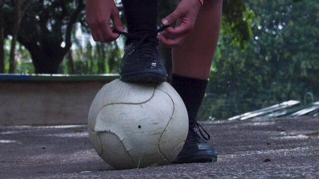 Close de menina amarrando cadarso de chuteira futebol feminino