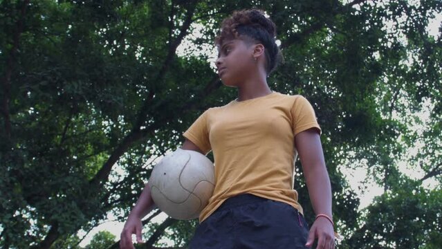 Atleta de futebol feminino segurando bola de futebol contra ao sol empoderada negra brazil afro