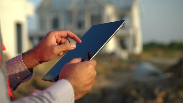 Close up tablet for checking and maintenance to inspection at modern home building construction. Architect using tablet and application in construction site.
