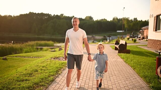 Happy father and son walk holding hands outdoors at sunset. Time together, holidays.Father's Day, Children's Day Generative AI