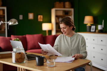 Smiling woman examining her bank statement at home office