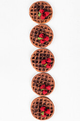 Round Chocolate waffles with raspberries. White background. Top view