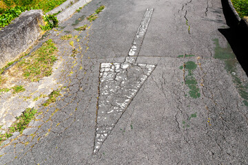 Fototapeta premium Reverse direction arrow on a weathered asphalt road
