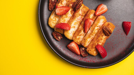 Delicious appetizer of deep-fried cheese with jam under strawberries on a yellow background.