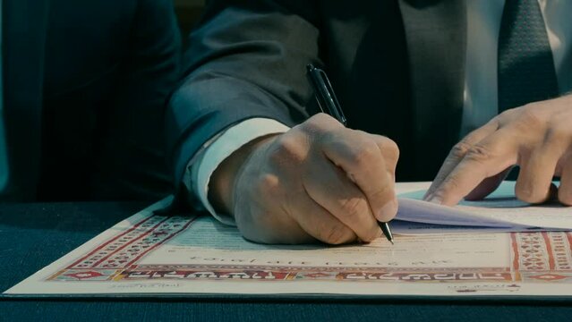 A rabbi sits at a table and fills in details in a ketubah. High quality FullHD footage Generative AI